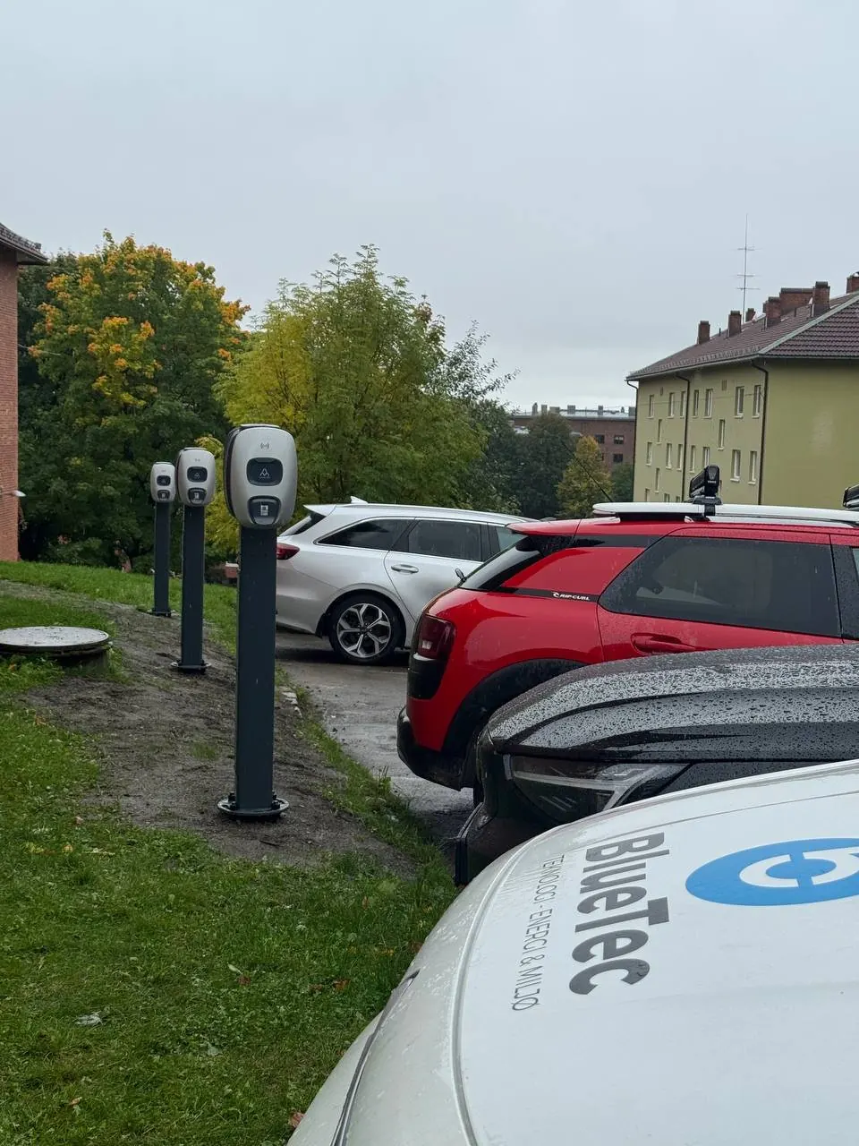 Ladestolper ved parkeringsplass i borettslag, med BlueTec-bil i forgrunnen